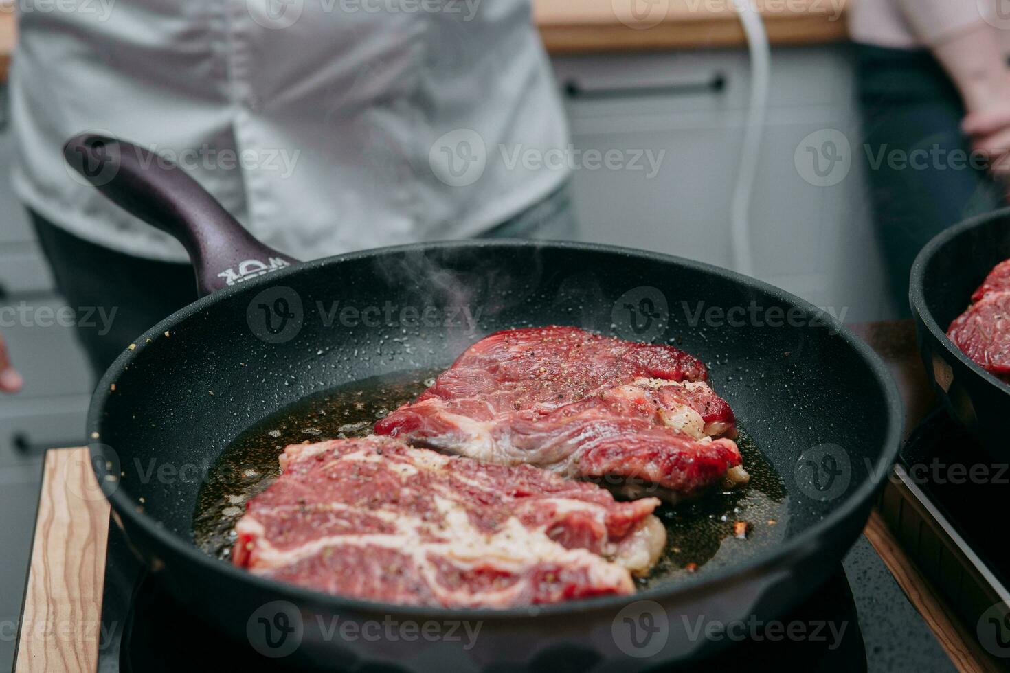 Cooking beef ribeye steak in a frying pan in the cooking class. Steak with spices. Cooking process, close-up. photo