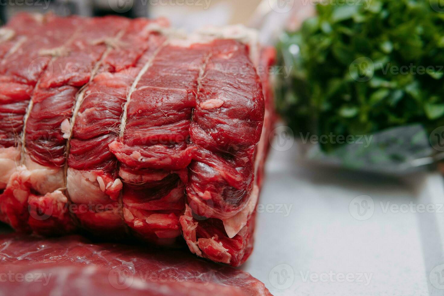 Aged beef for cooking steak in a cooking class. Raw beef and greens, close-up. photo