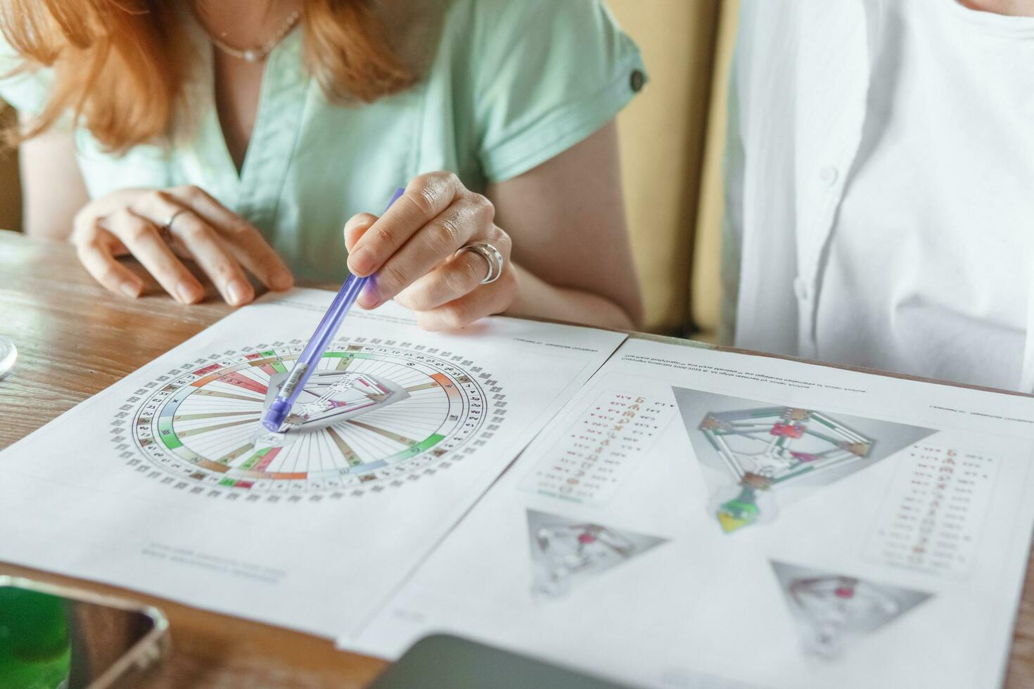 Tver, Russia - August 2, 2021. A woman in a cafe at a table is studying the design of a person. The concept of studying esoteric sciences. A bodigraph or a map of a person on an A4 sheet. photo