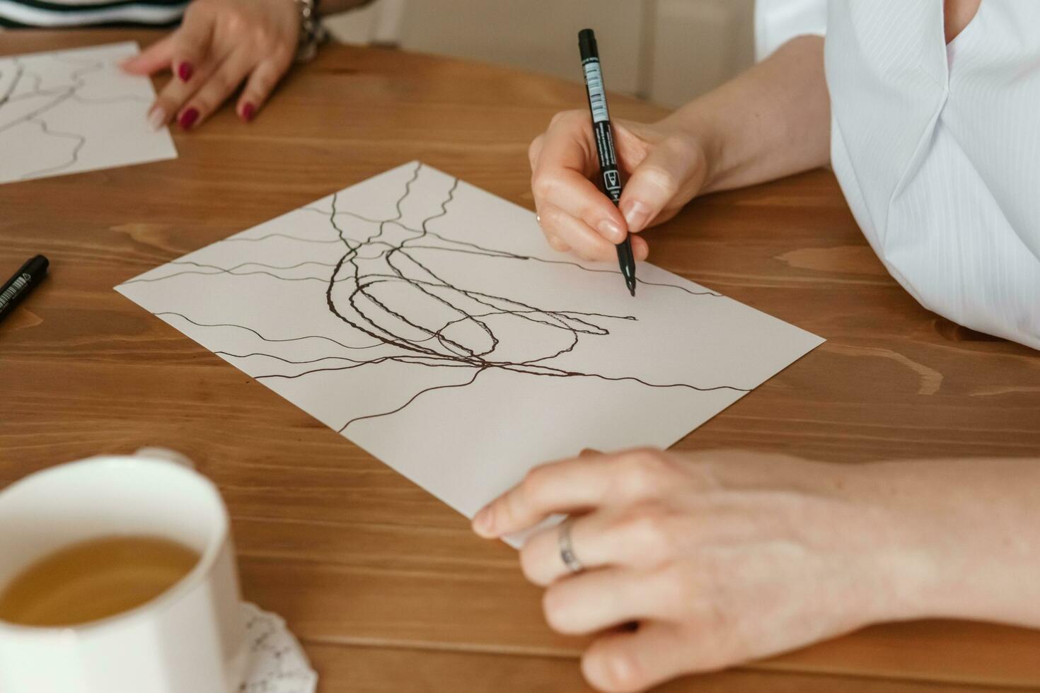 TVER, RUSSIA - FEBRUARY 25, 2023. Woman draws neurographics at table at a psychological session, neurographic pencil drawing to remove restrictions, art therapy photo