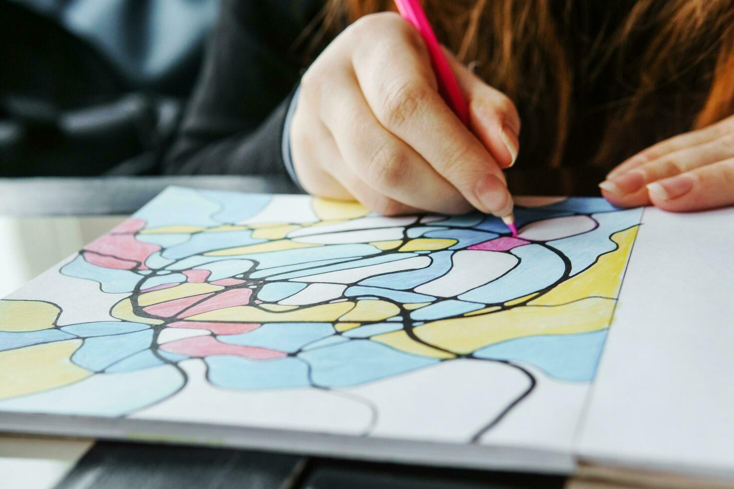 TVER, RUSSIA - FEBRUARY 11, 2023. a young woman draws neurography at a table at a psychological session, a neurographic resunok with a pencil to remove oranicheniy, art therapy. photo