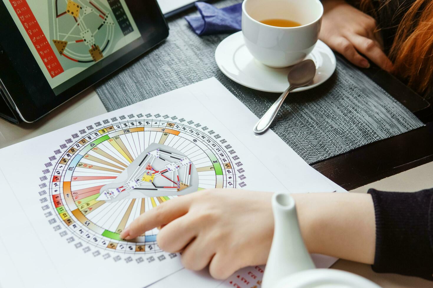 TVER, RUSSIA - FEBRUARY 12, 2023. A woman at the table is studying a rave mandala by human design. Rave mandala on the table close-up. The concept of esoteric teachings. photo