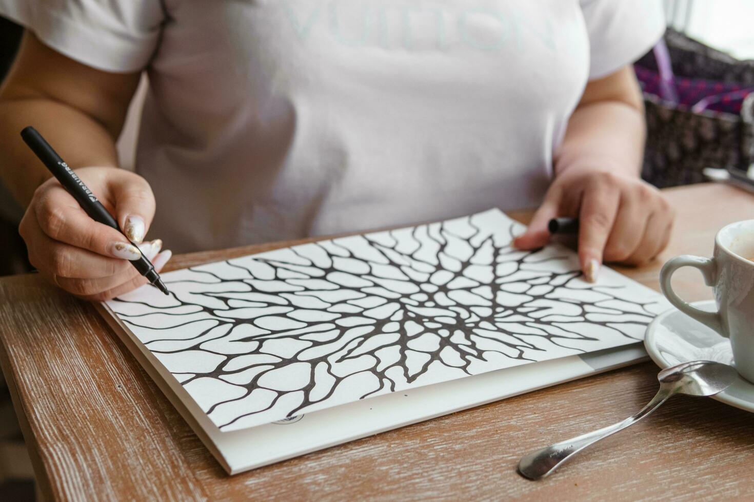 TVER, RUSSIA - FEBRUARY 25, 2023. Woman draws neurographics at table at a psychological session, neurographic pencil drawing to remove restrictions, art therapy photo