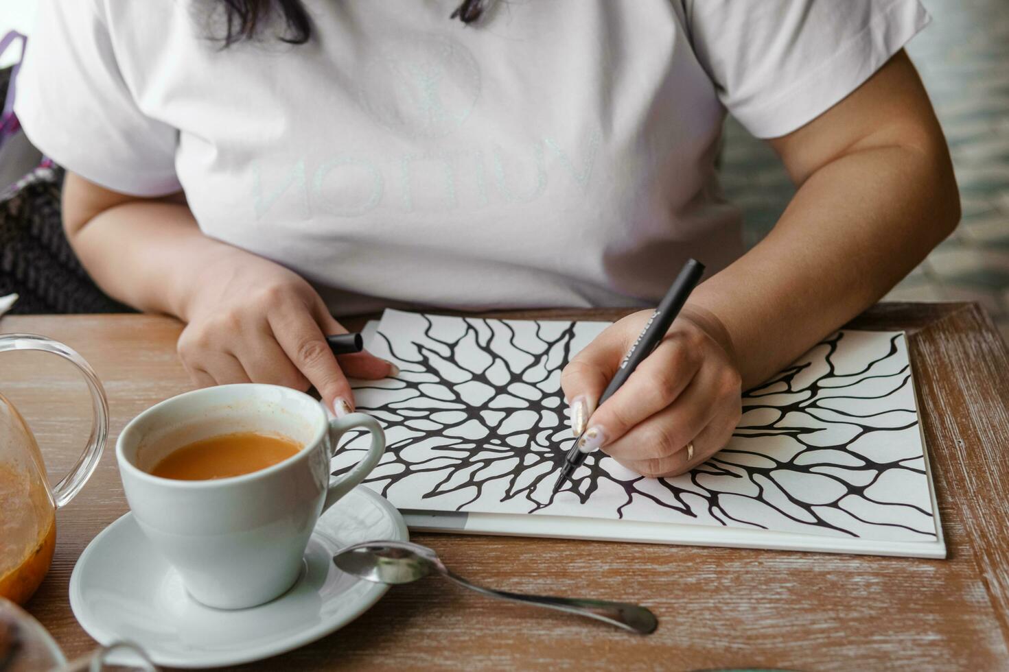 TVER, RUSSIA - FEBRUARY 25, 2023. Woman draws neurographics at table at a psychological session, neurographic pencil drawing to remove restrictions, art therapy photo