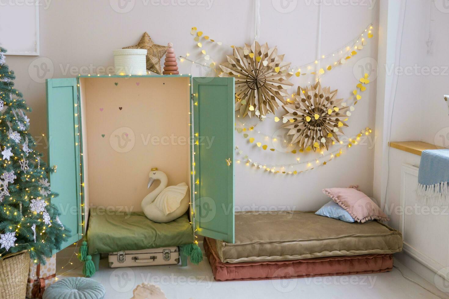 The interior of a children's room decorated for the Christmas holidays. A Christmas tree with garlands and a children's wardrobe with soft pillows. photo
