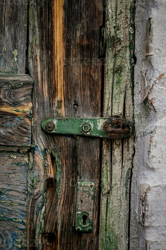 An old lock hinge on a cracked wooden door. Vintage Door photo