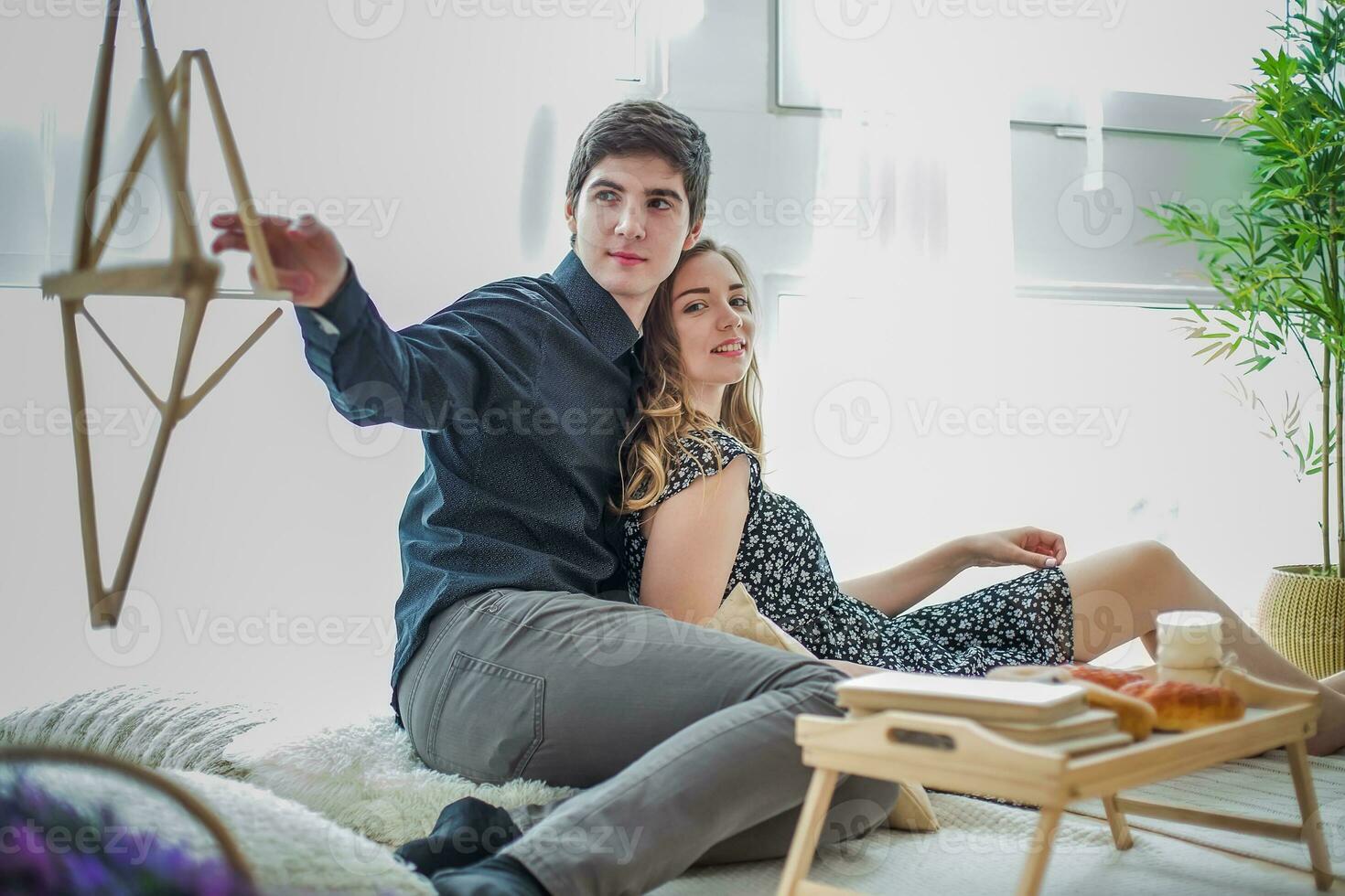 el chico con el niña sentado a el ventana en contra el antecedentes de almohadas foto