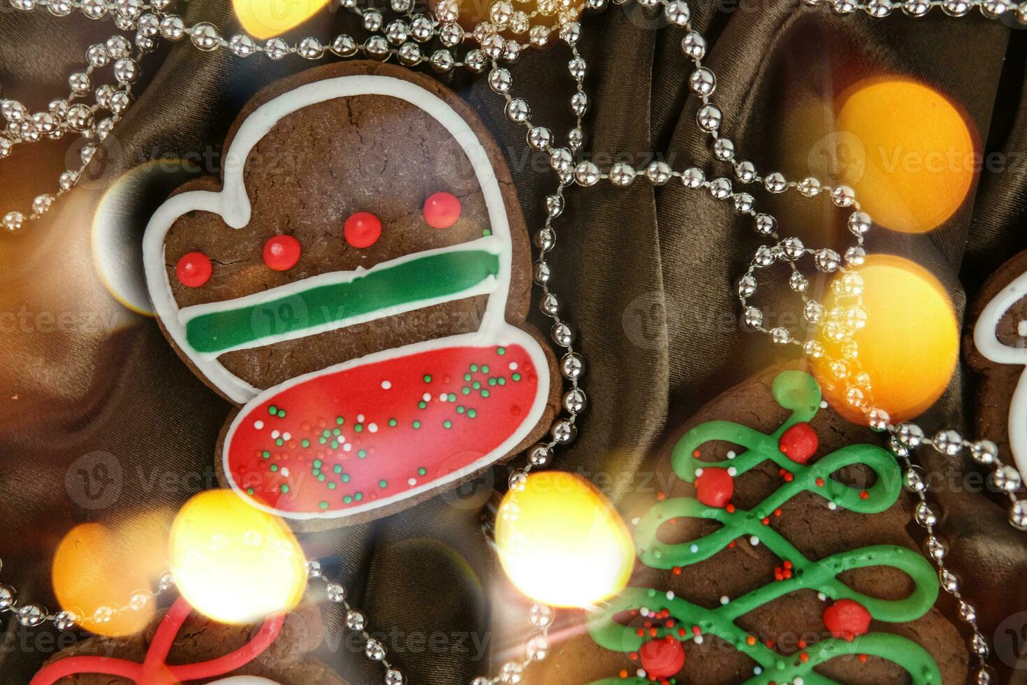 Banner for Christmas and New Year gingerbread. Christmas trees, toys, snowmen, garlands on a background of brown silk fabric. Bright bokeh. photo