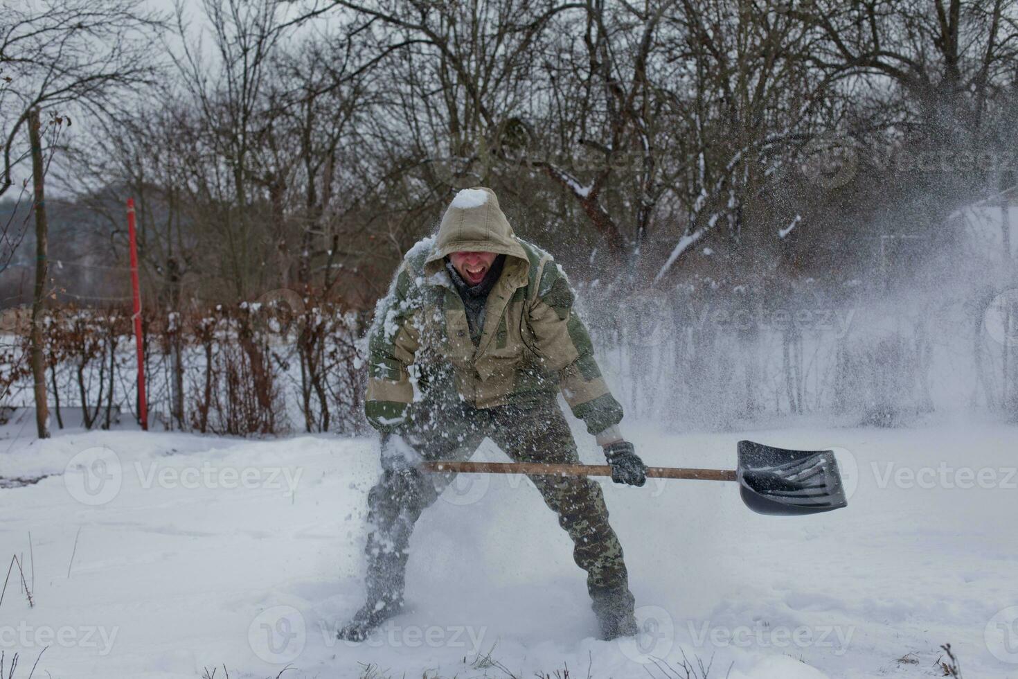 man clears the yard of snow With Shovel. Heavy snowfall in winter. High level of snow. Snowy snowdrift. photo