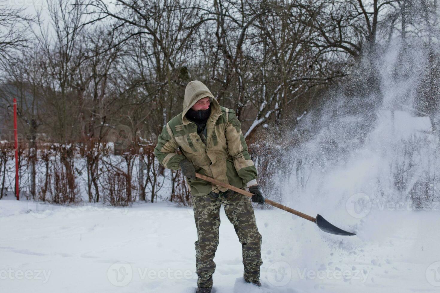 man clears the yard of snow With Shovel. Heavy snowfall in winter. High level of snow. Snowy snowdrift. photo