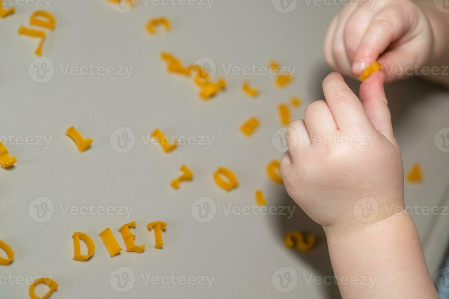 hand of child collecting letters from pasta from table. development of fine motor skills of hands. Montessori technique. Learn letters and alphabet in game photo