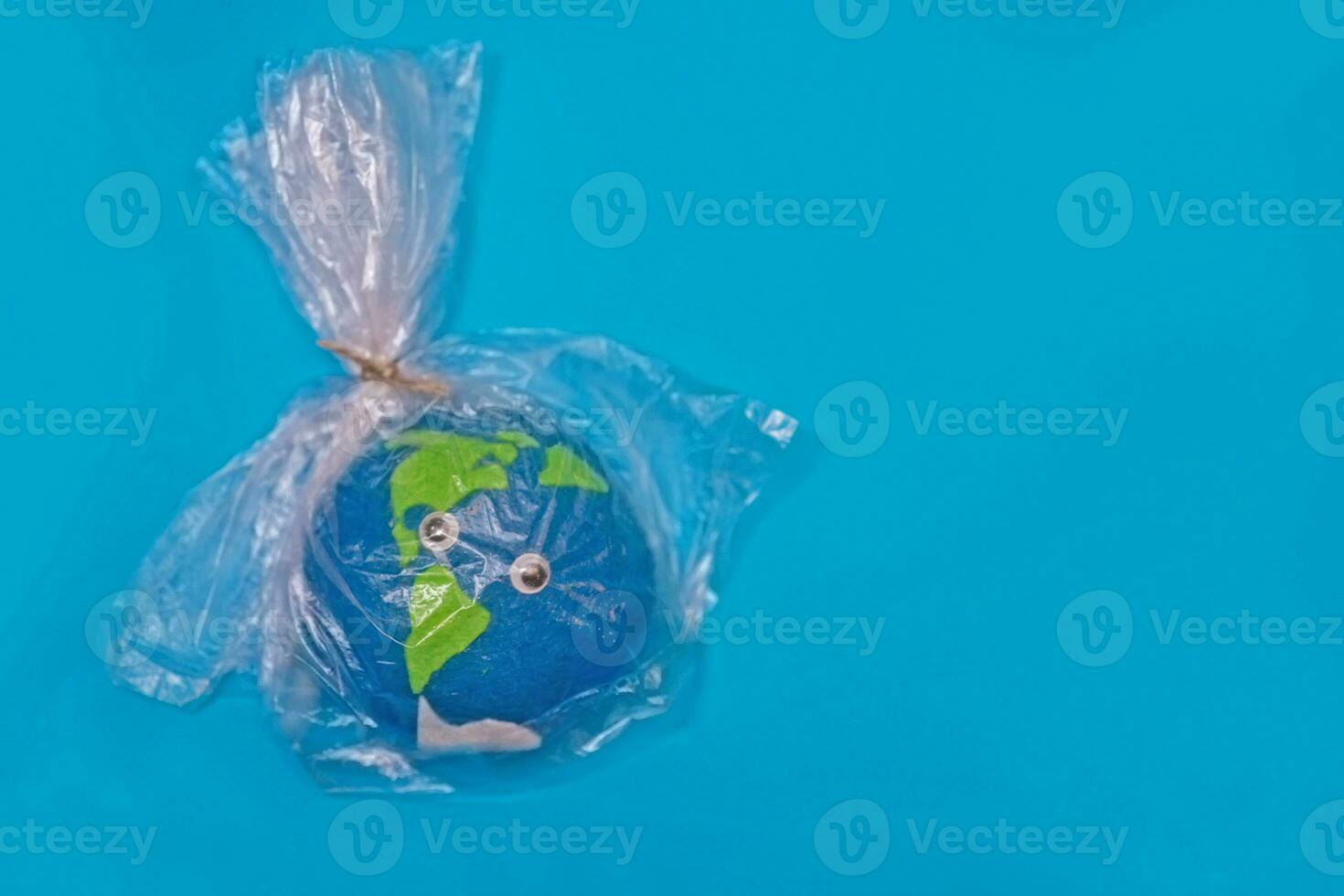 Model of Trapped Planet Earth in plastic bag on blue background. concept of pollution by plastic debris. warming due to greenhouse effect. Day Eatrh. photo