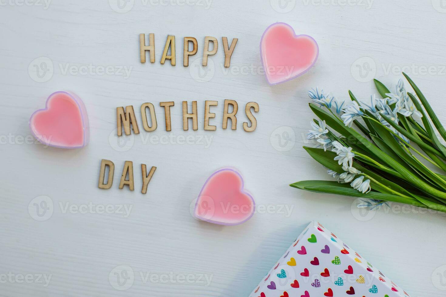 Text HAPPY MOTHER'S DAY on white wooden background. bouquet of blue flowers and box of gifts for mother. Greetings for Mother's day. Top view. photo