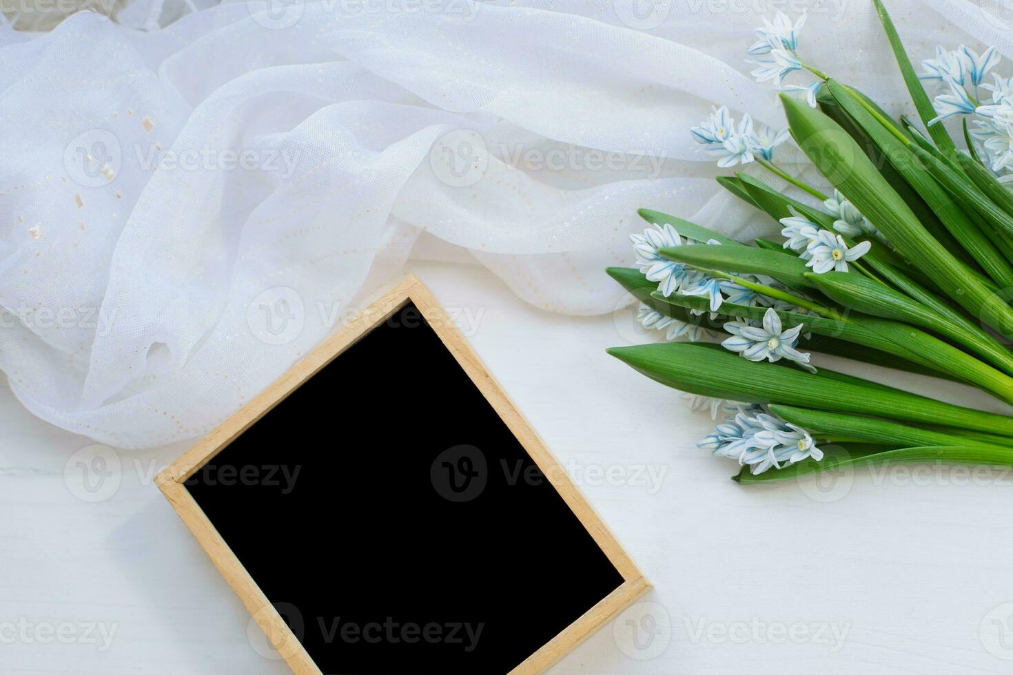 empty wooden frame with place for text lies on table next to bouquet of flowers. background for spring card. Concept March 8, Women's Day. Copy space. photo