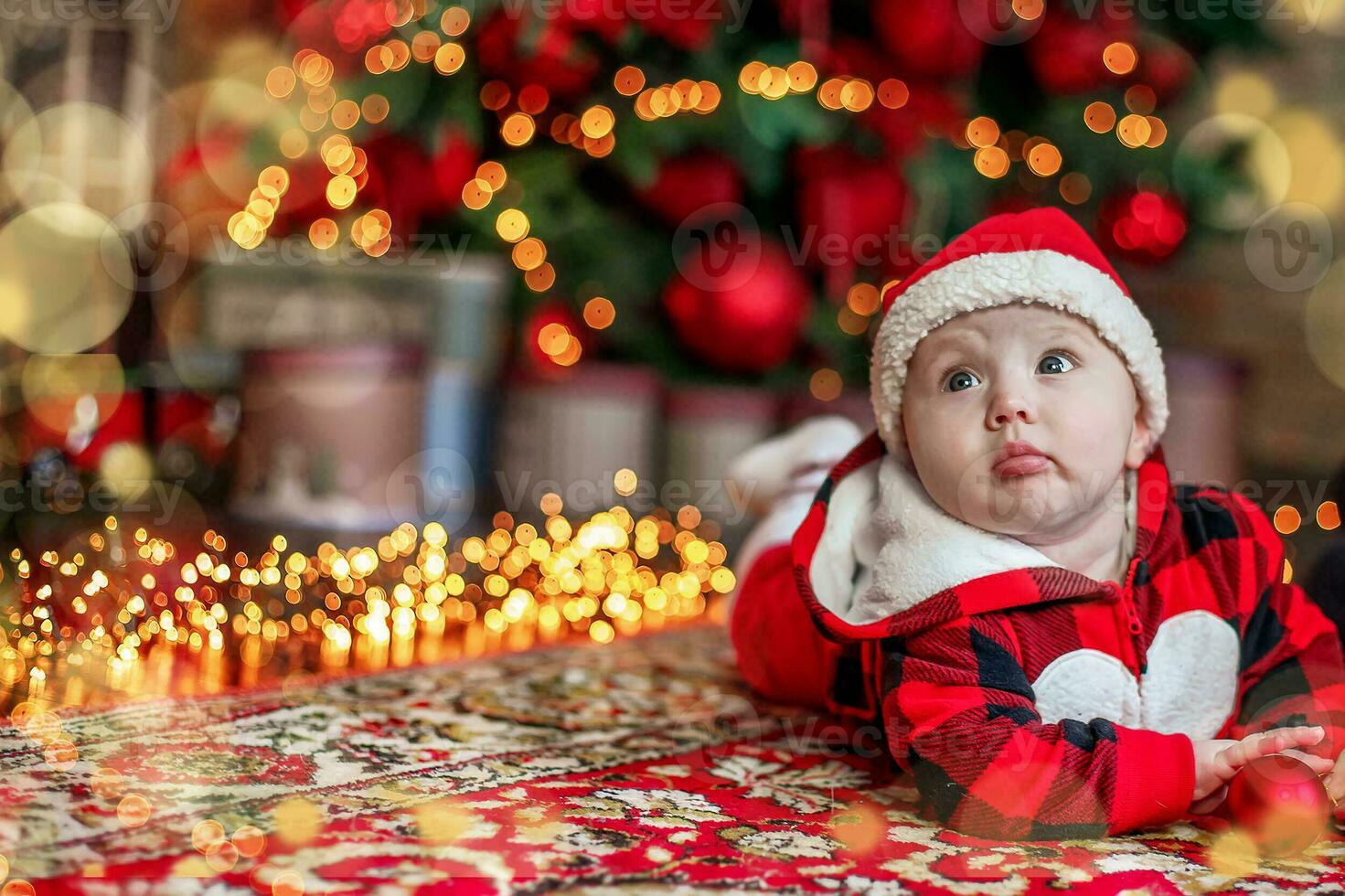 Little six month old baby dressed as Santa Claus. Background for christmas card. The child looks up at the place for inscription. photo