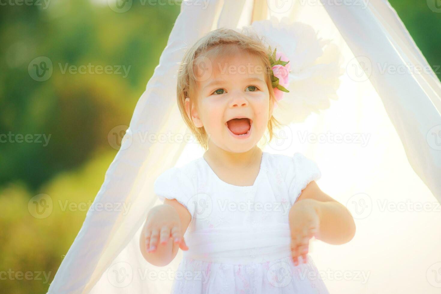 The child screaming with joy, standing against a background tent for games. photo