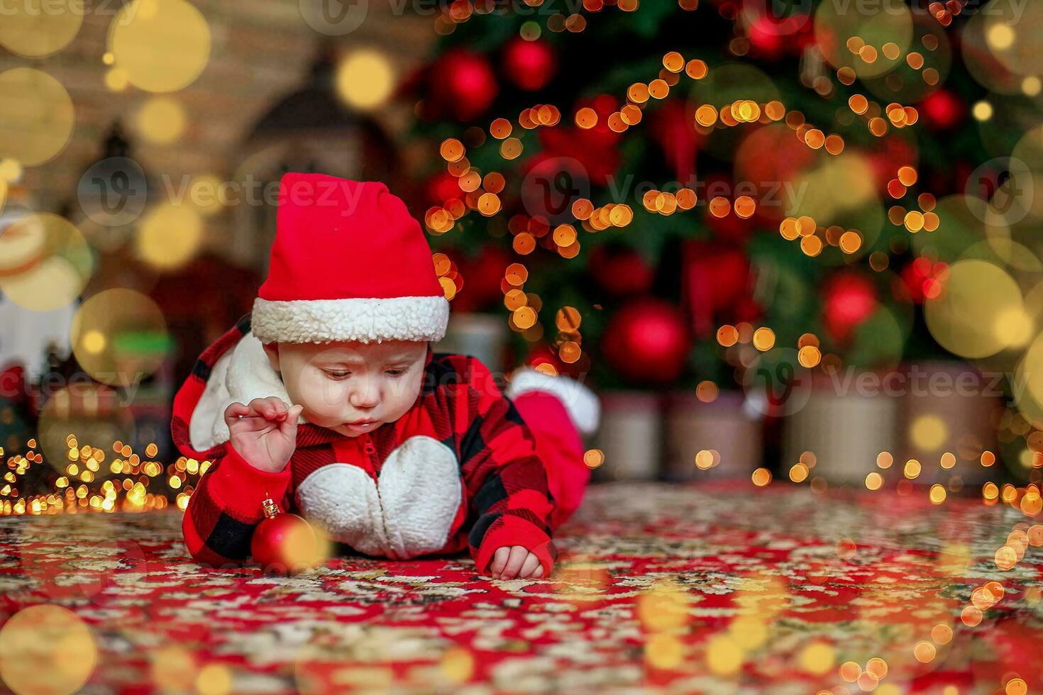 Little six month old baby dressed as Santa Claus. Background for christmas card. The child looks down at the place for inscription. photo