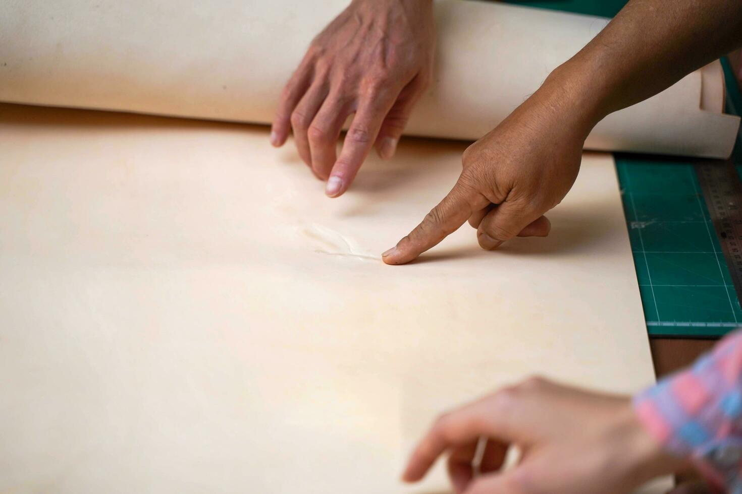 Closeup and crop hands of leather craftsman pointing at the flaw of the white leather photo