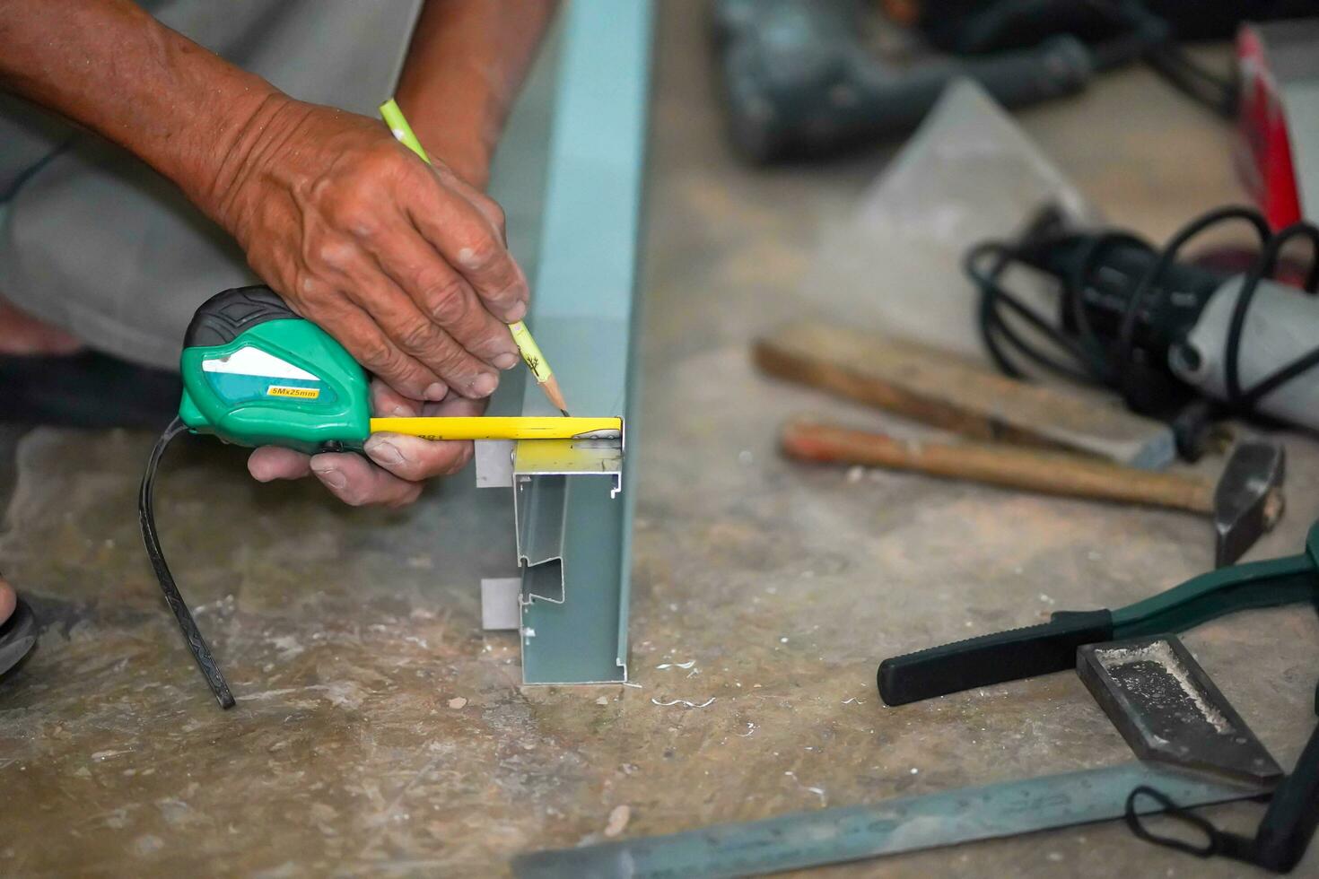 Closeup hands of builder using a pencil marks out the details before cutting aluminum lumber at construction site. photo