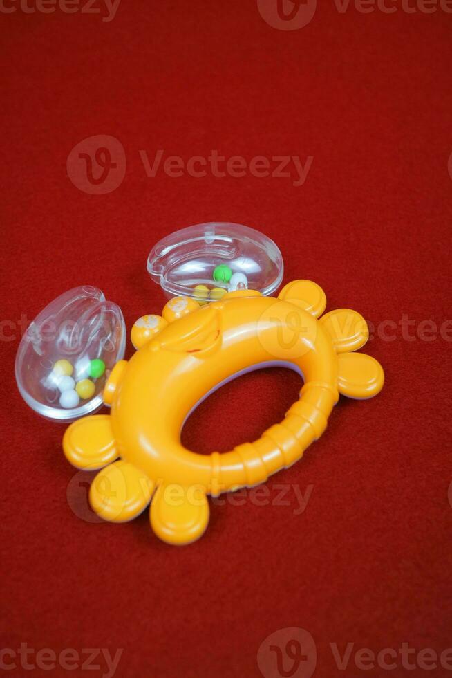 Yellow crab shaped children's toy, with small balls inside, makes a loud sound. On red background photo