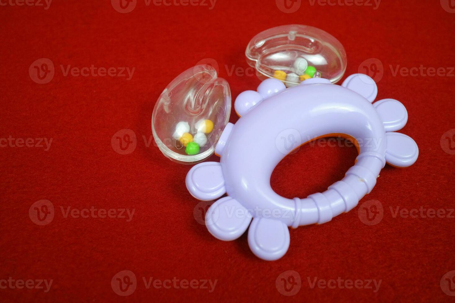 Purple crab shaped children's toy, with small balls inside, makes a loud sound. On red background photo