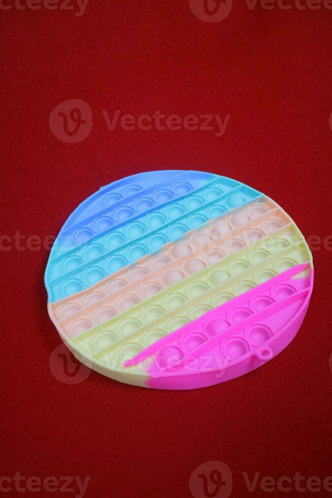 Colorful fidget pop toys, circular shape, which function to reduce stress. on red background photo