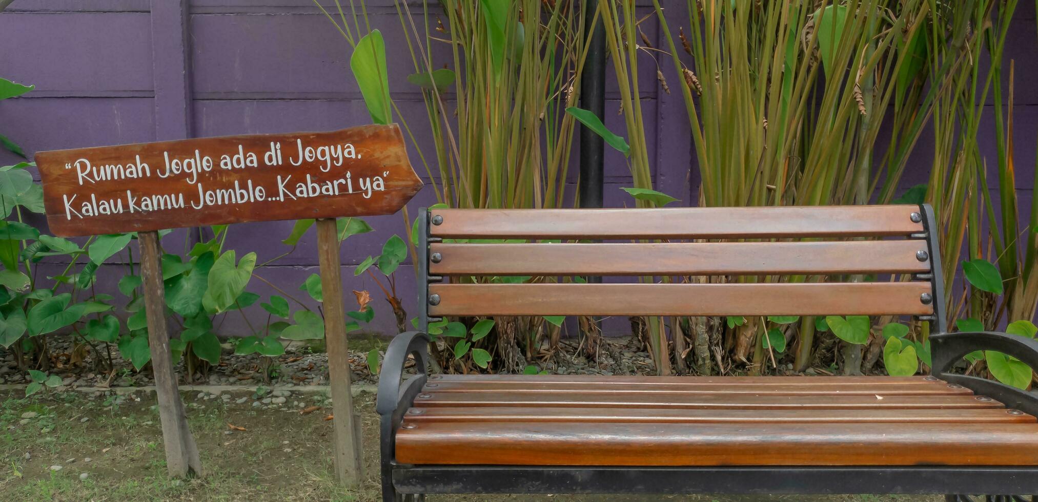 The front of the brown wooden chair is near a series of leaves with writing beside it. photo