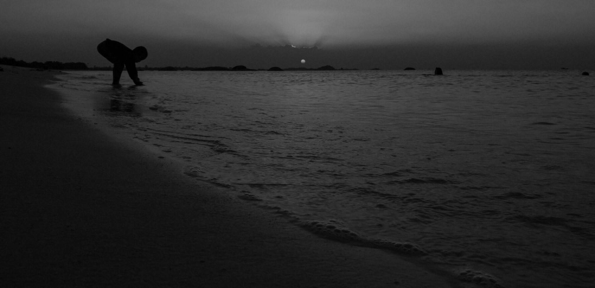 Silhouette of people touching the sea in a Black and White view photo