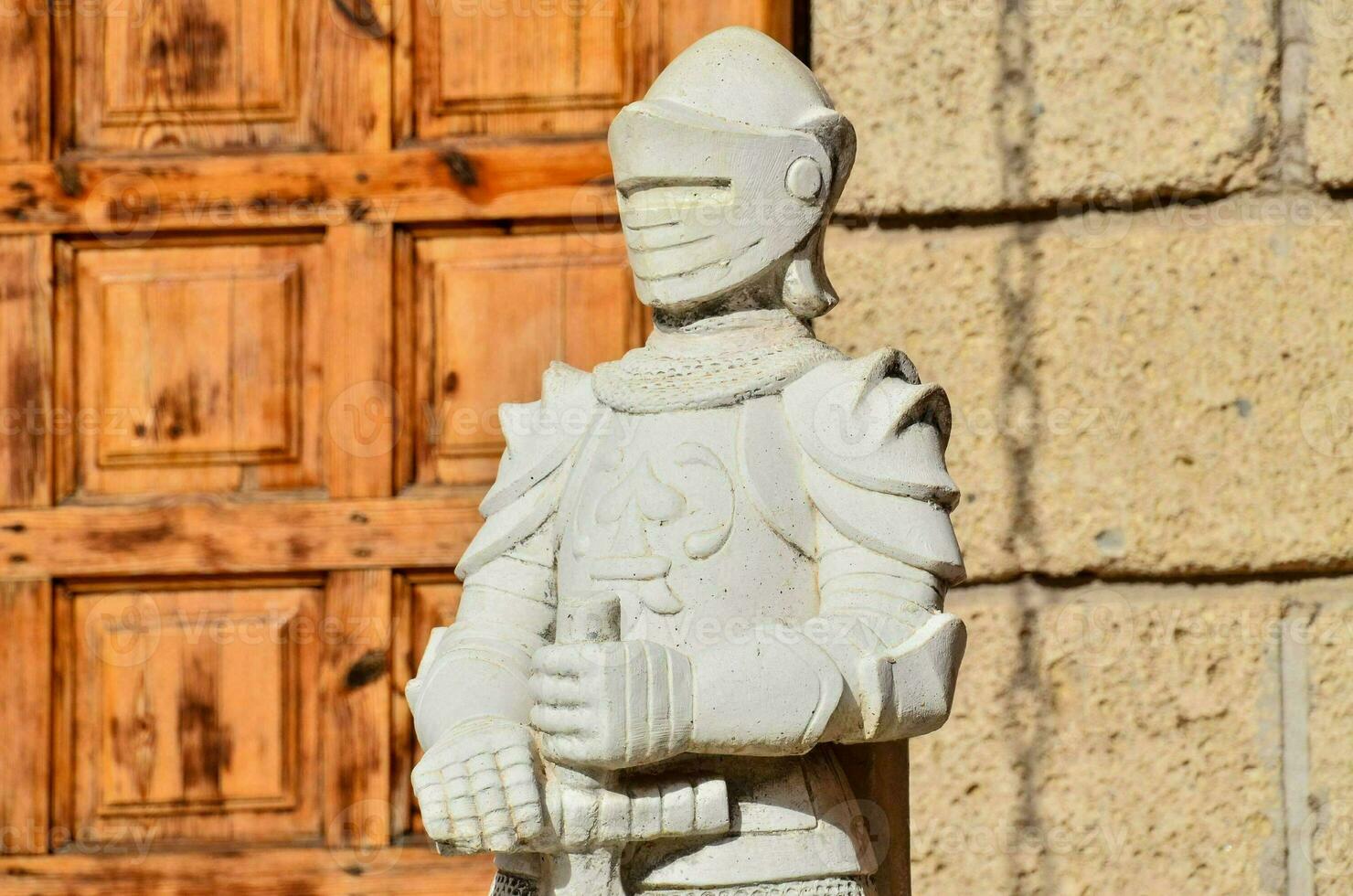 a statue of a knight standing in front of a wooden door photo