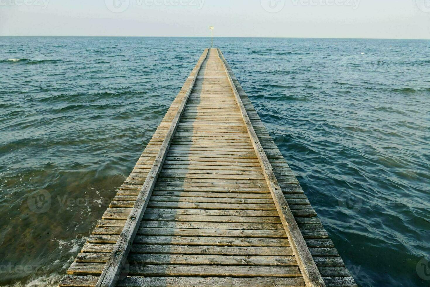 a wooden pier stretches out into the ocean photo