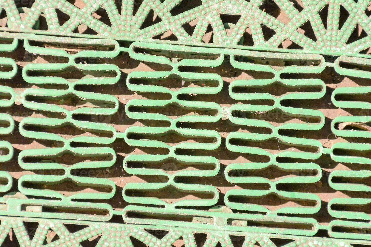 a green metal grate with a pattern of geometric shapes photo