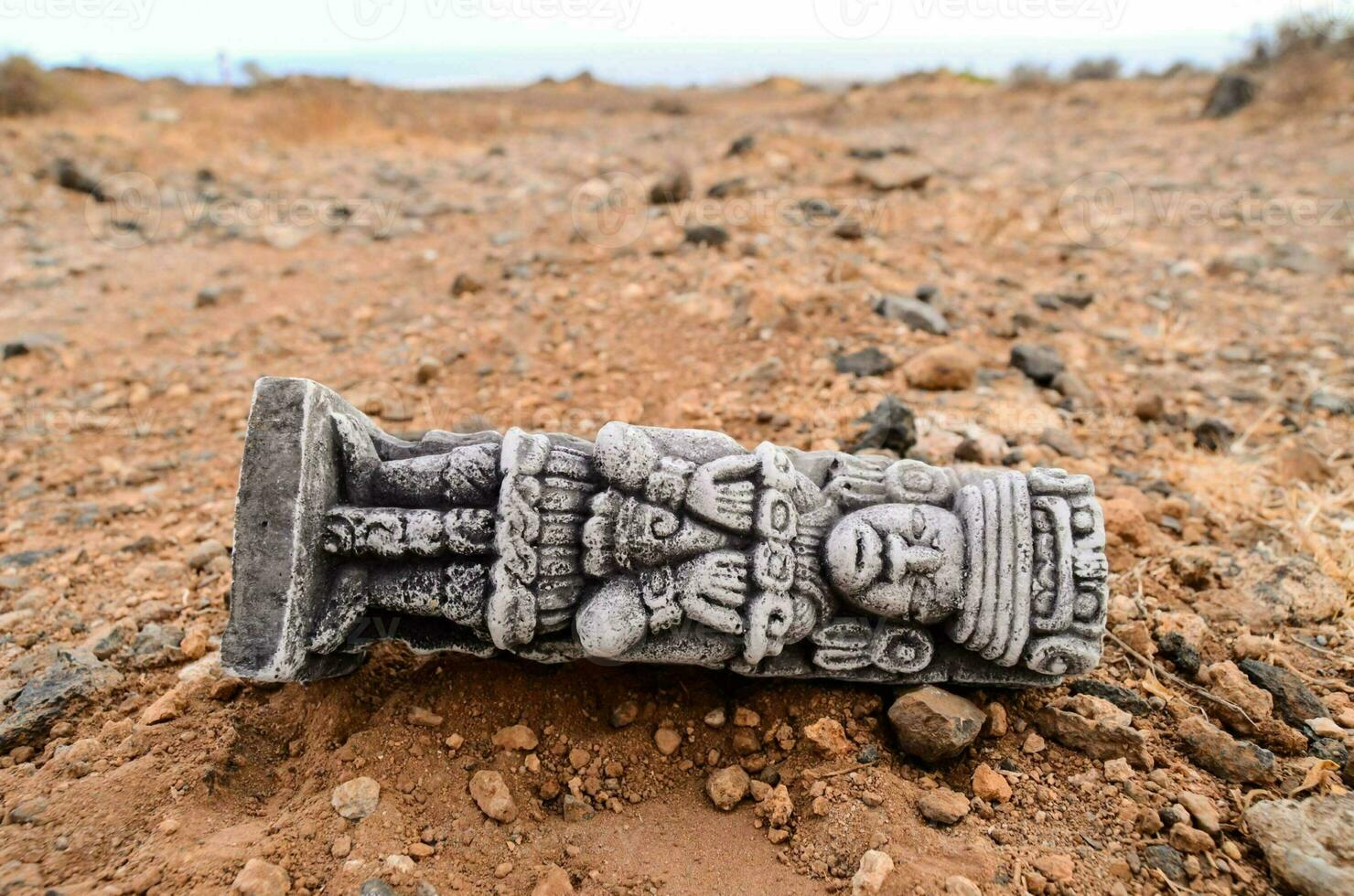 a stone statue laying on the ground in the desert photo