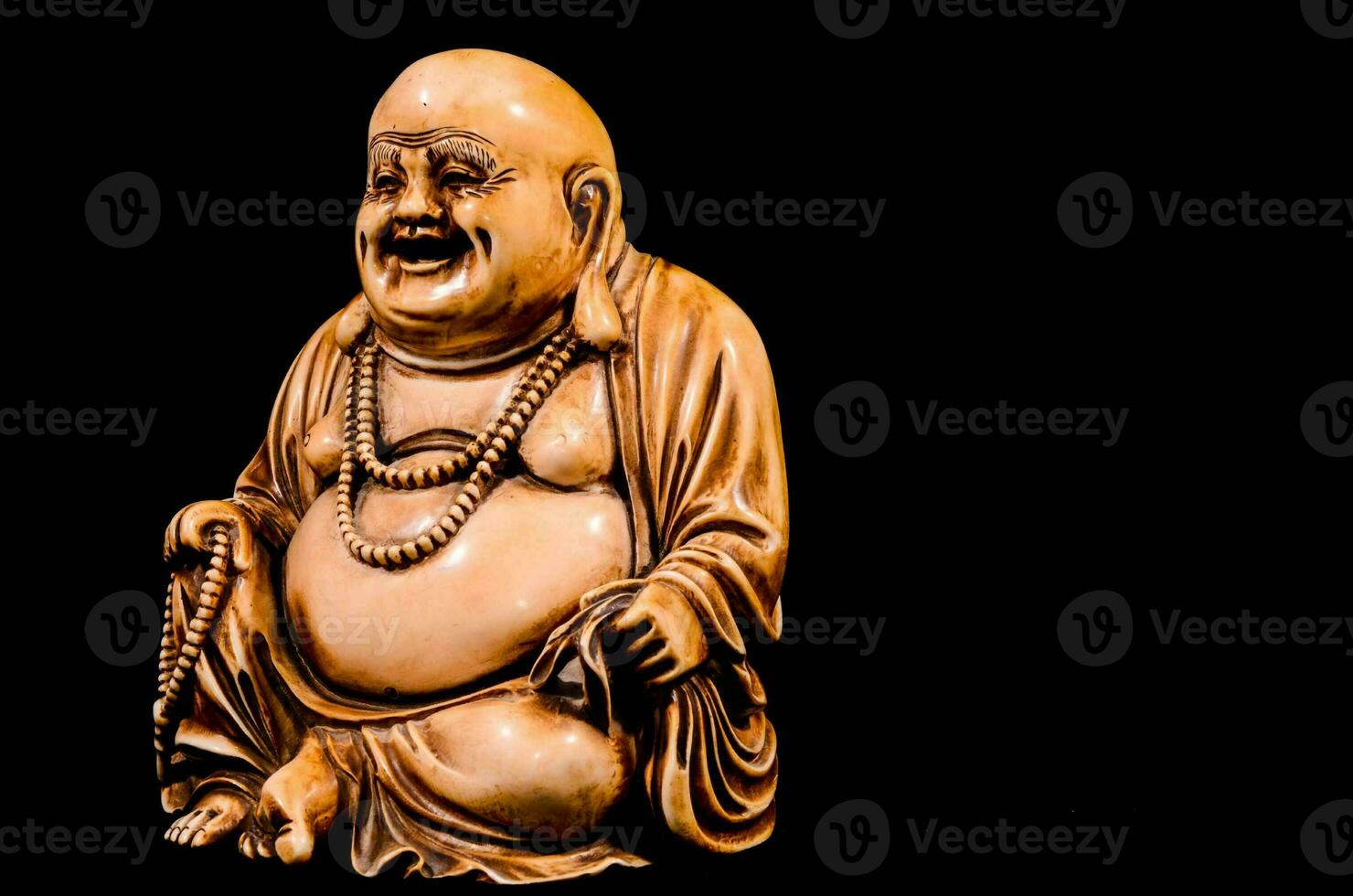 a statue of a laughing buddha sitting on a black background photo