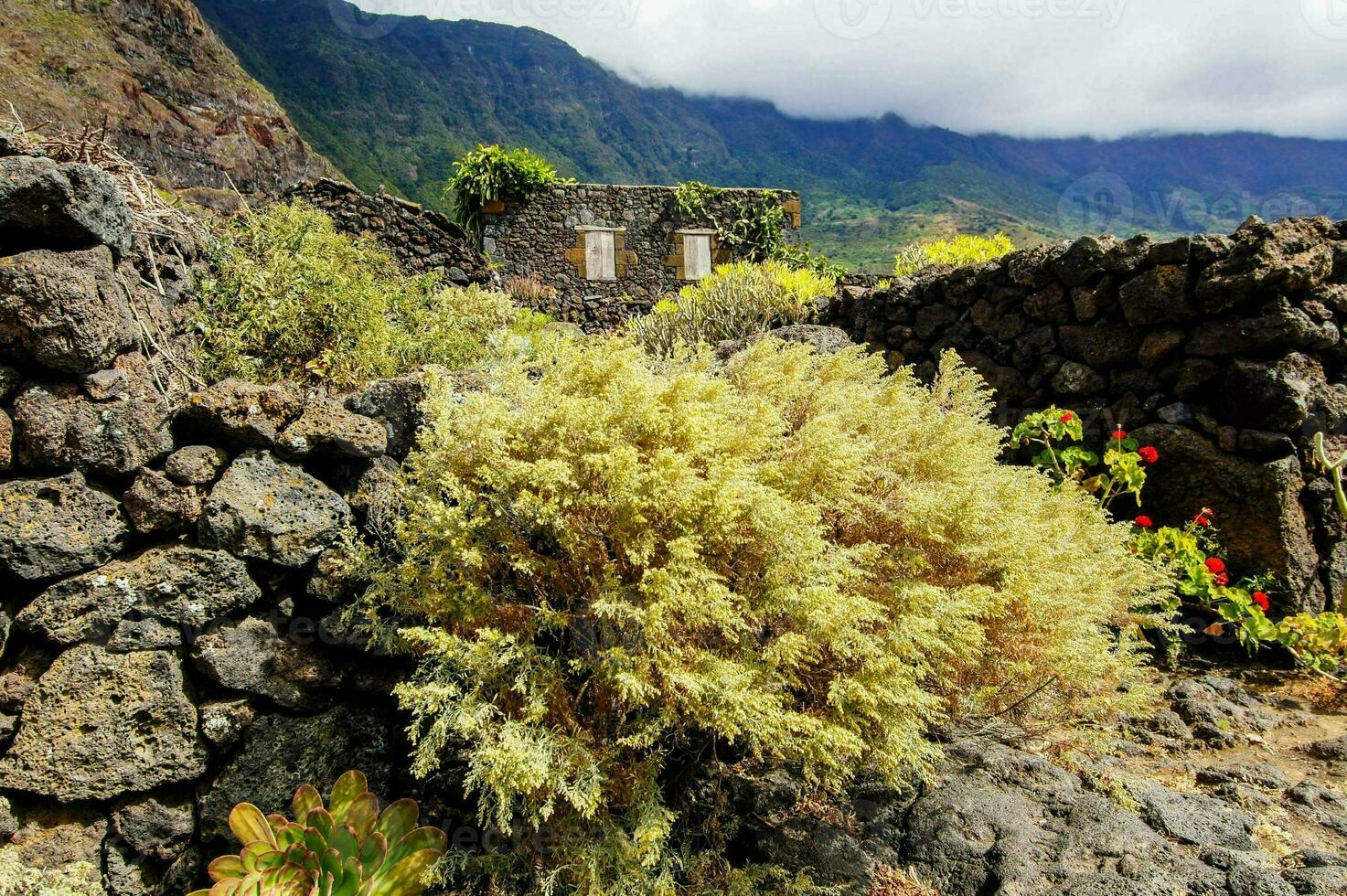 a stone wall and a small building in the middle of a rocky area photo