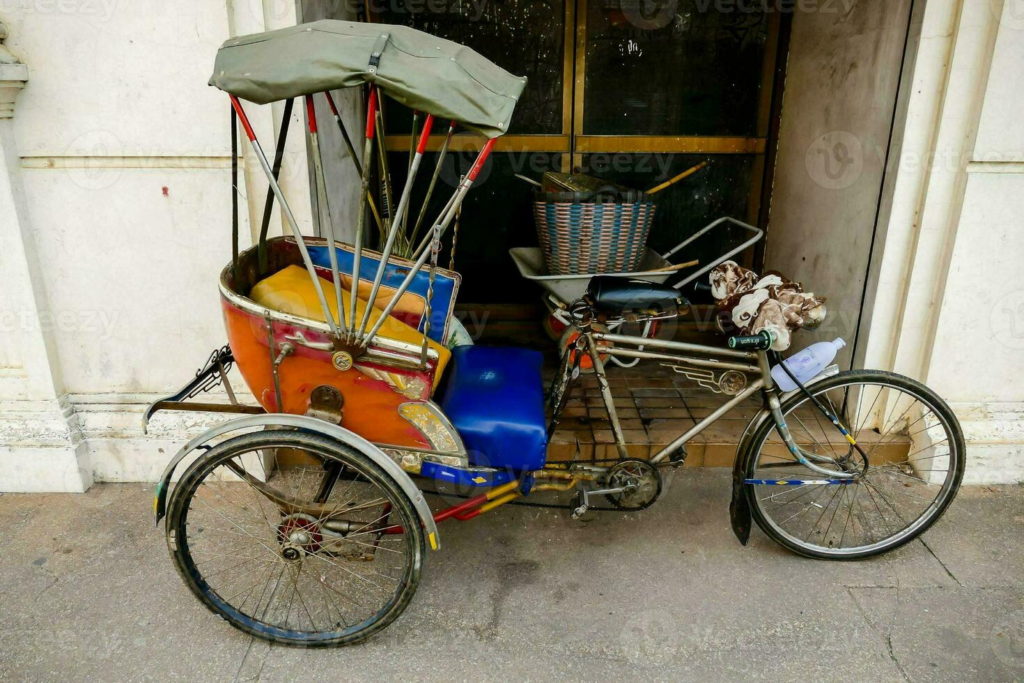 a rickshaw with a basket and umbrella parked outside a building photo