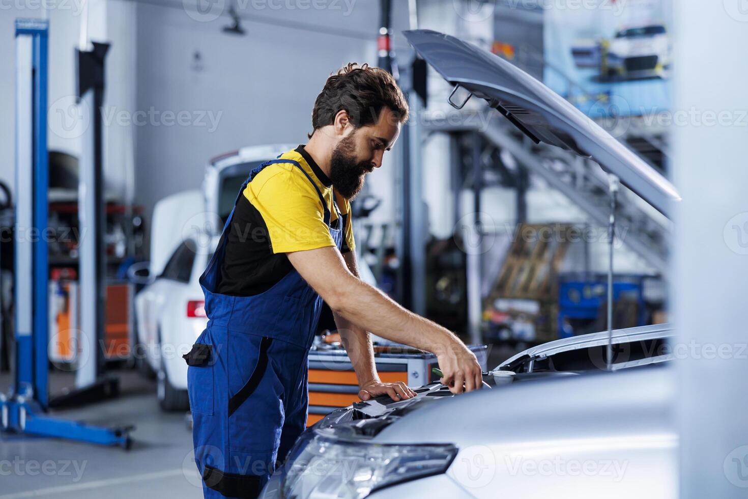 Meticulous specialist in car service using professional mechanical tool to repair broken engine. Specialist in garage fixing client automobile, ensuring optimal automotive performance photo
