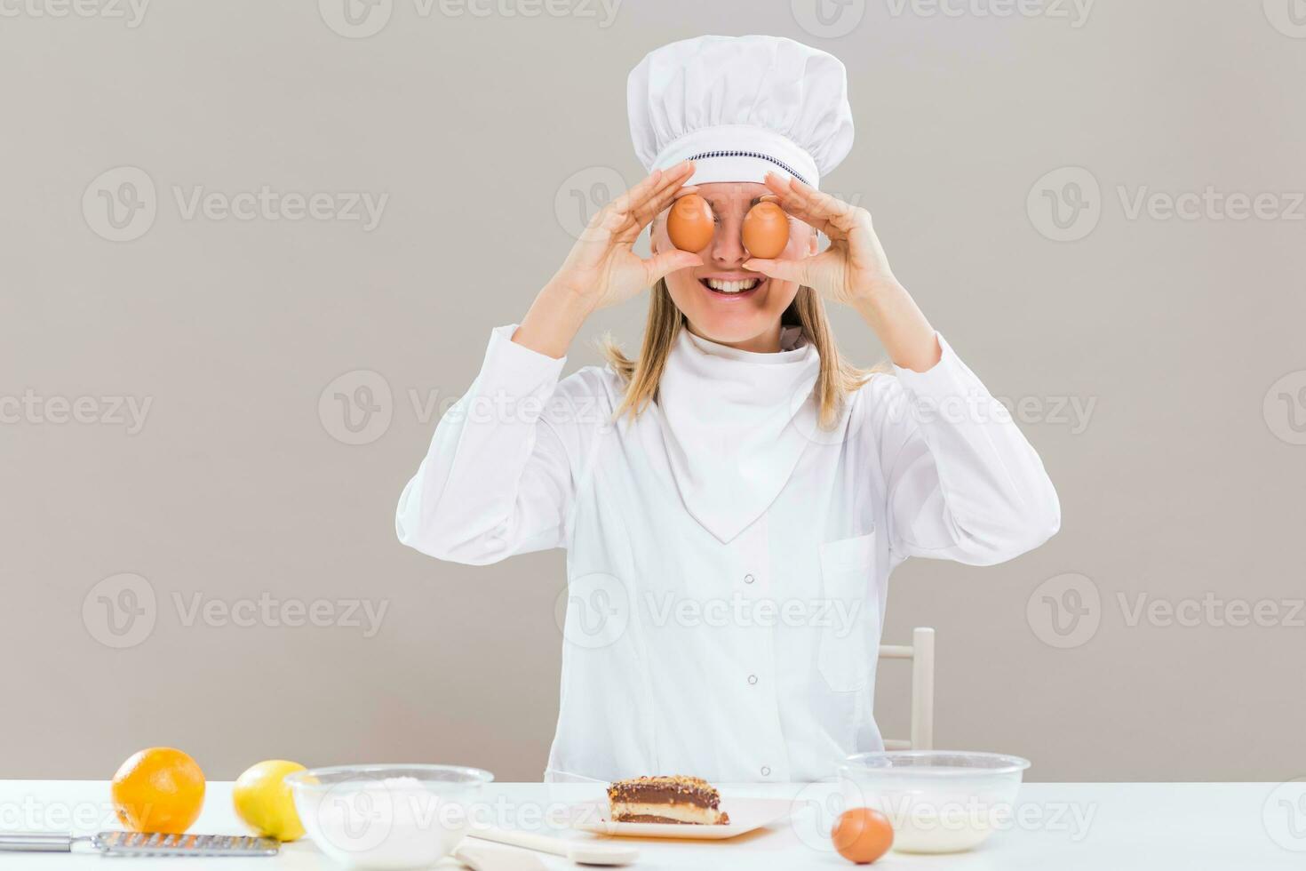 Female confectioner covering her eyes with eggs photo