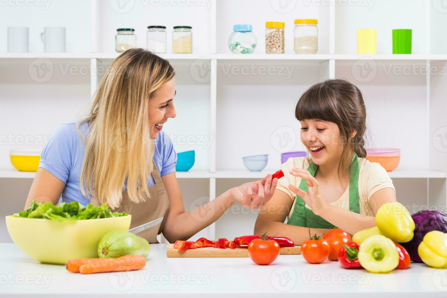 Happy mother and her daughter enjoy making healthy meal together at their home. photo