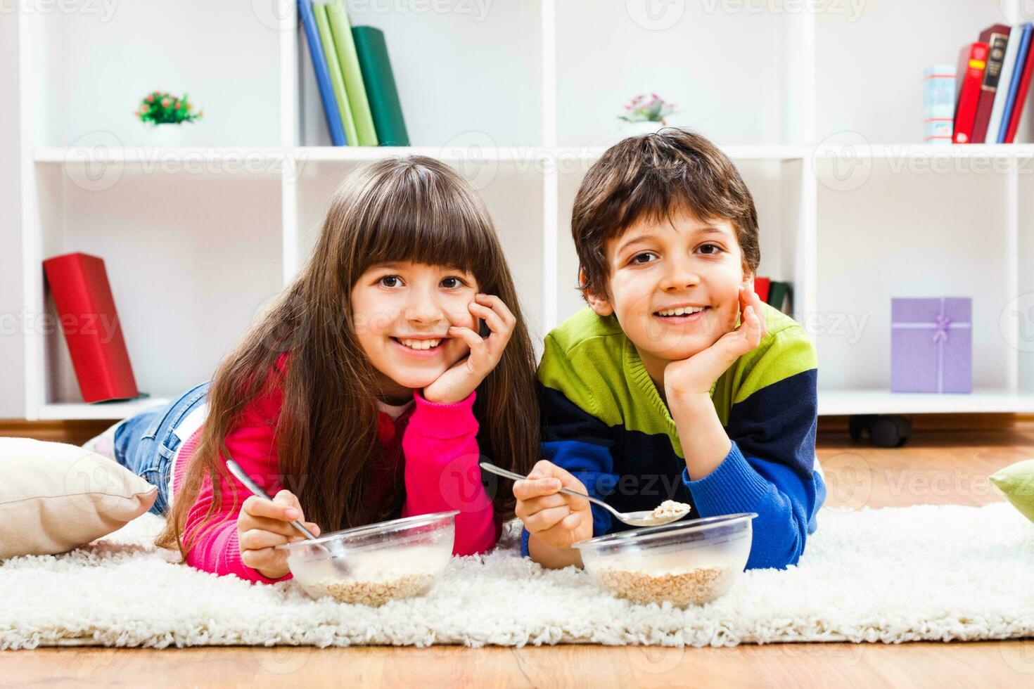 Two children eating cereal on the floor photo