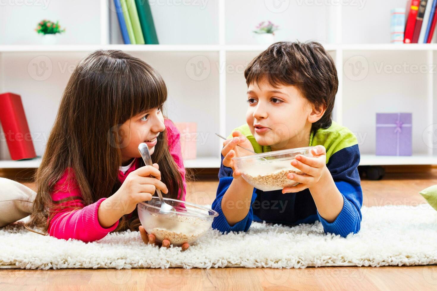 Two children eating cereal on the floor photo