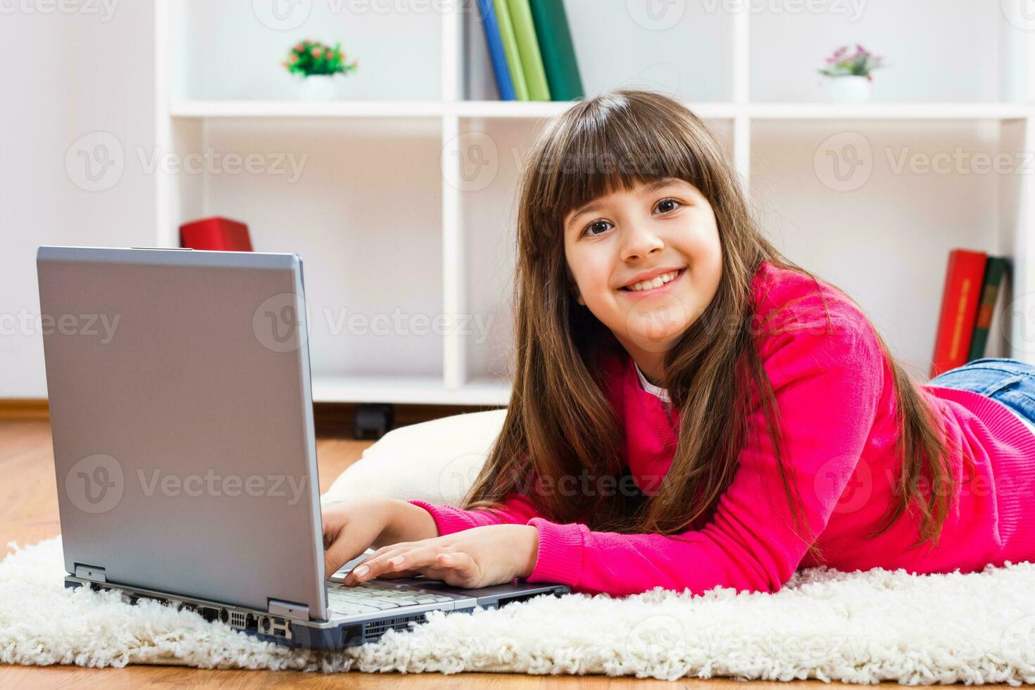 Litlle girl laying on the floor with a laptop photo