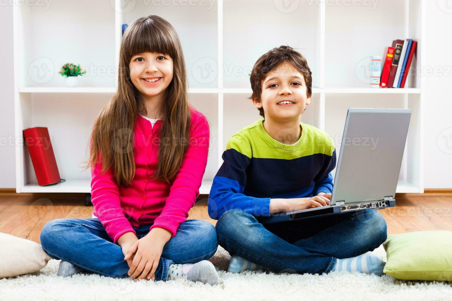 Two children sitting on the floor with a laptop photo