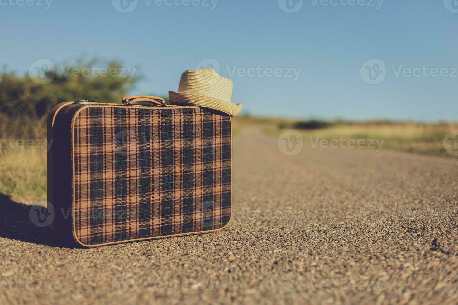 Image of  old suitcase and  hat  on the country road. photo
