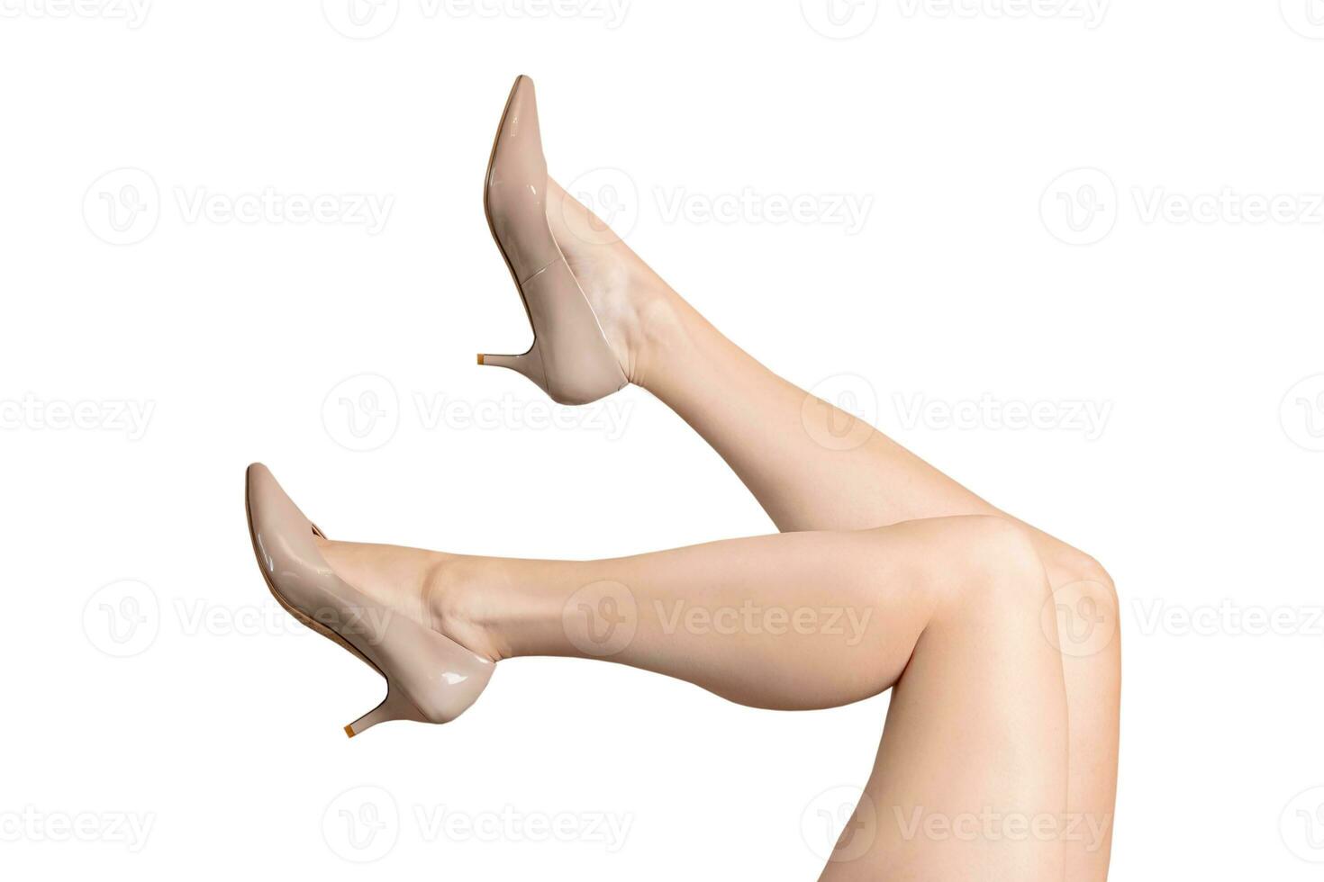 Womans legs in beige patent leather shoes hi heels isolated on white background photo