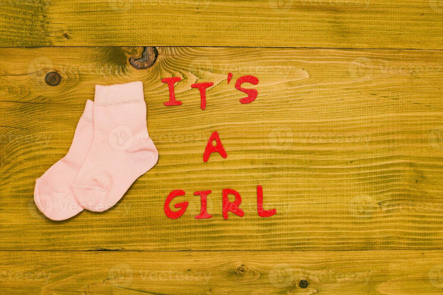 Text it's a girl with  little baby girl socks on wooden table photo
