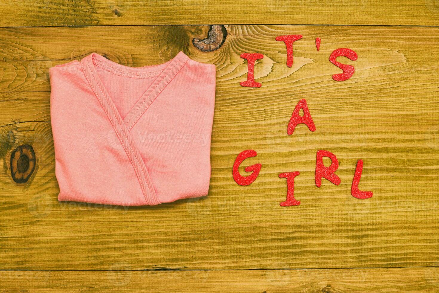 Text it's a girl with baby supplies and heart shape  on wooden table photo