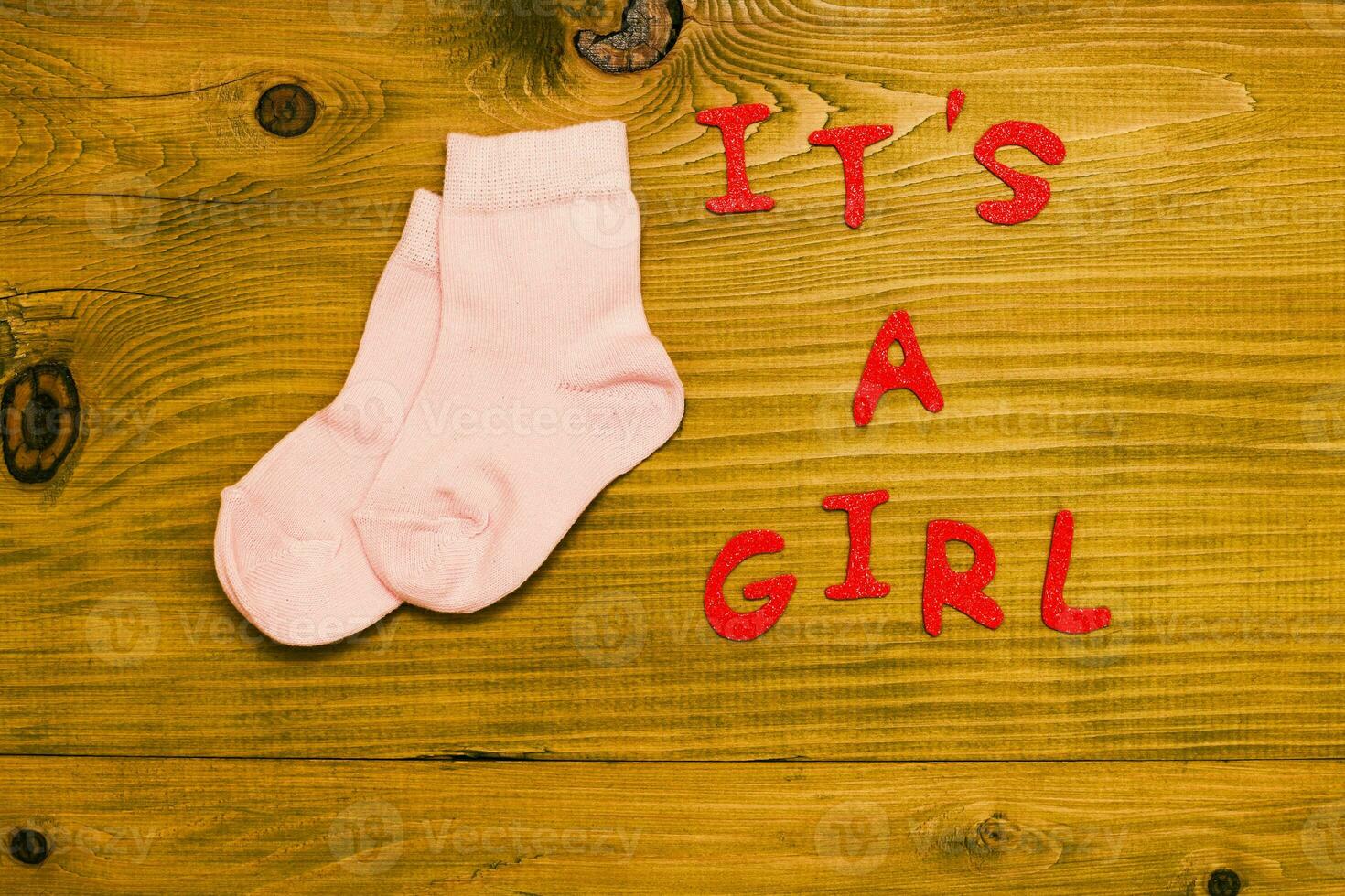 Text it's a girl with  little baby girl socks on wooden table photo