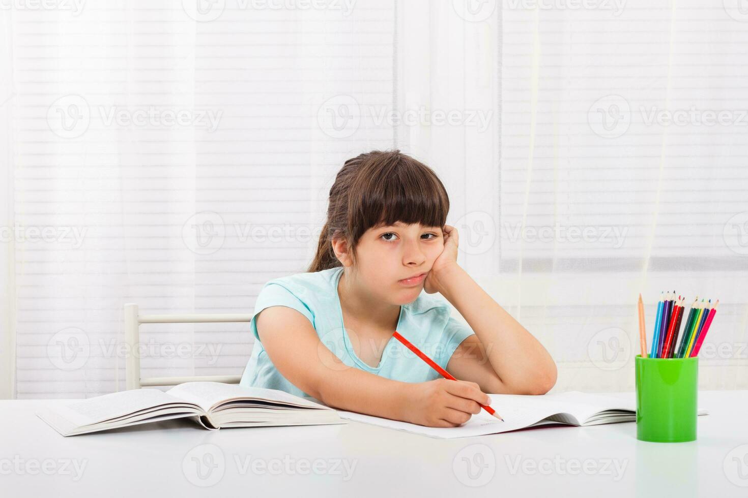 Little girl must stay at home and do her homework,but she would rather play outside. photo