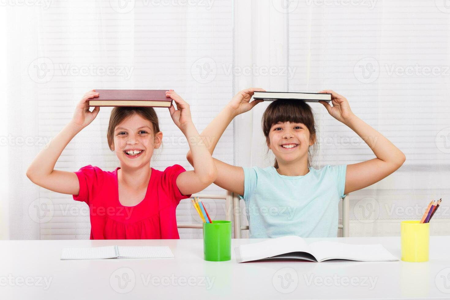 Happy little girls are sitting at the table and doing their homework. photo
