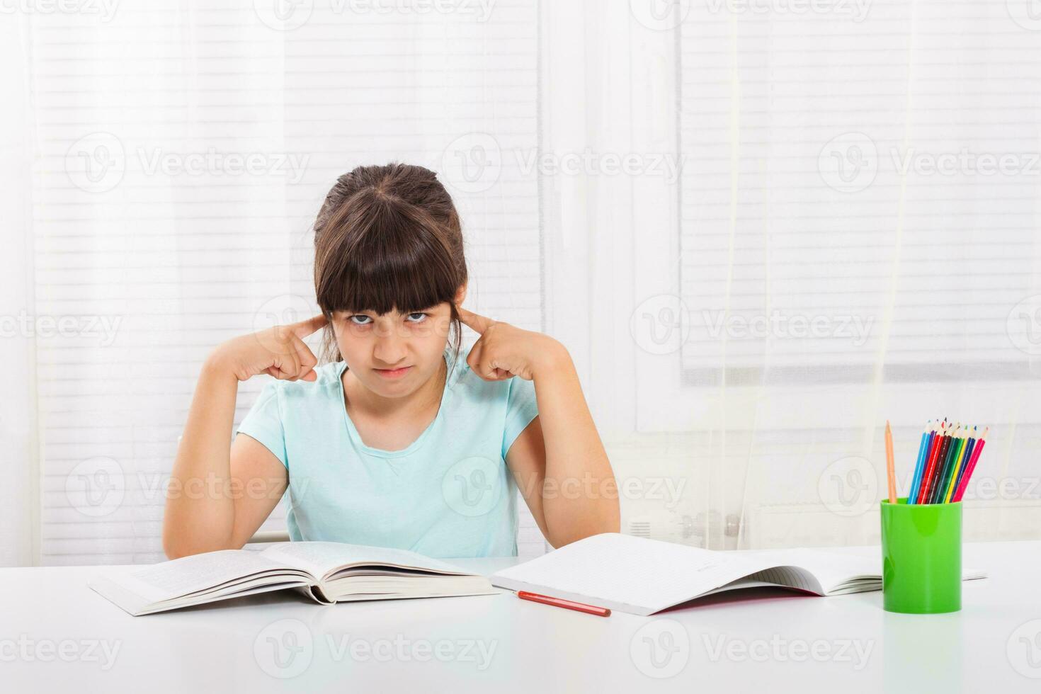 Angry little girl must stay at home and do her homework,but she would rather play outside. photo